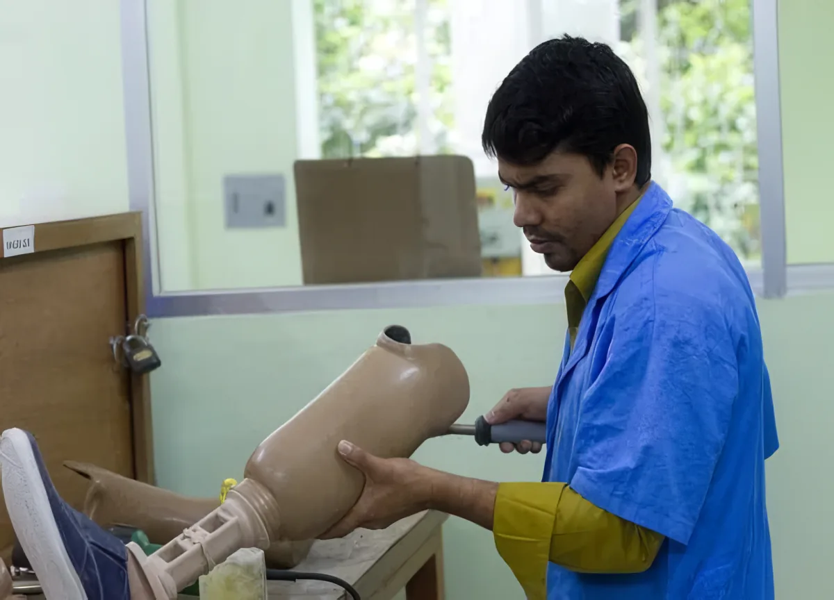 A technician fitting a prosthetic limb in the CRP workshop